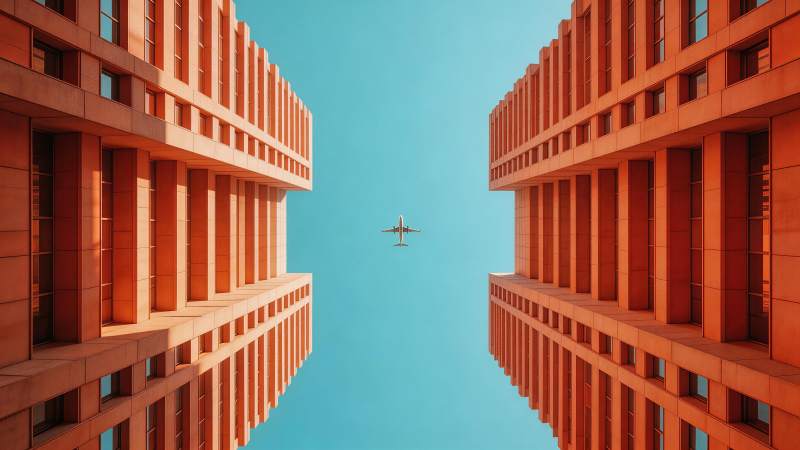 橙色高楼间飞行的客机仰视视角图片