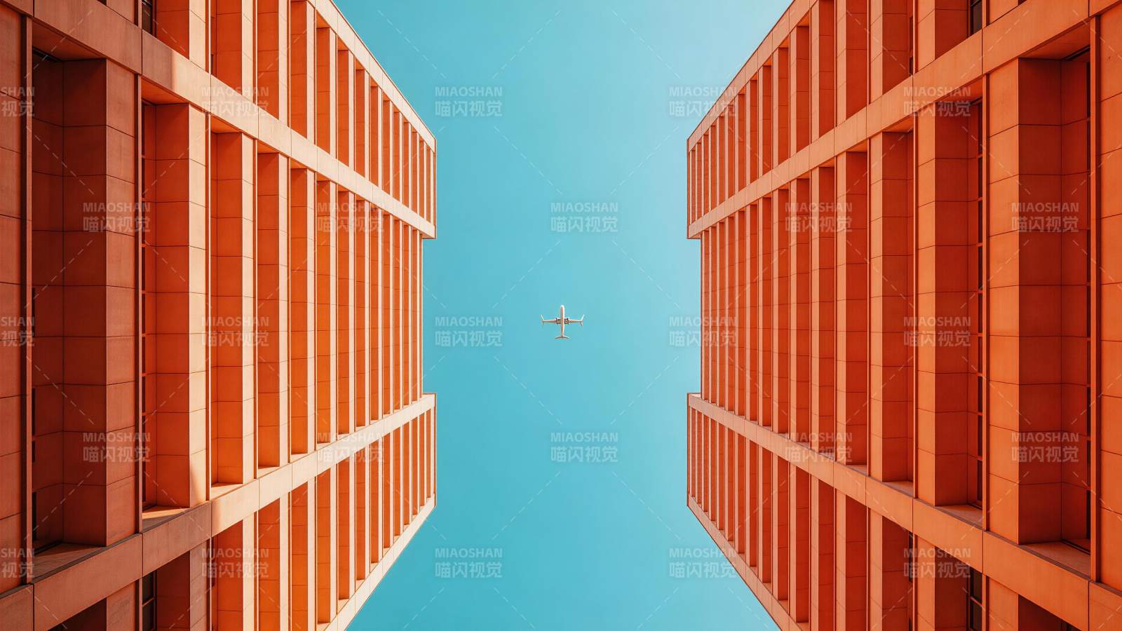 两栋橙色高楼间飞行的客机仰视图图片