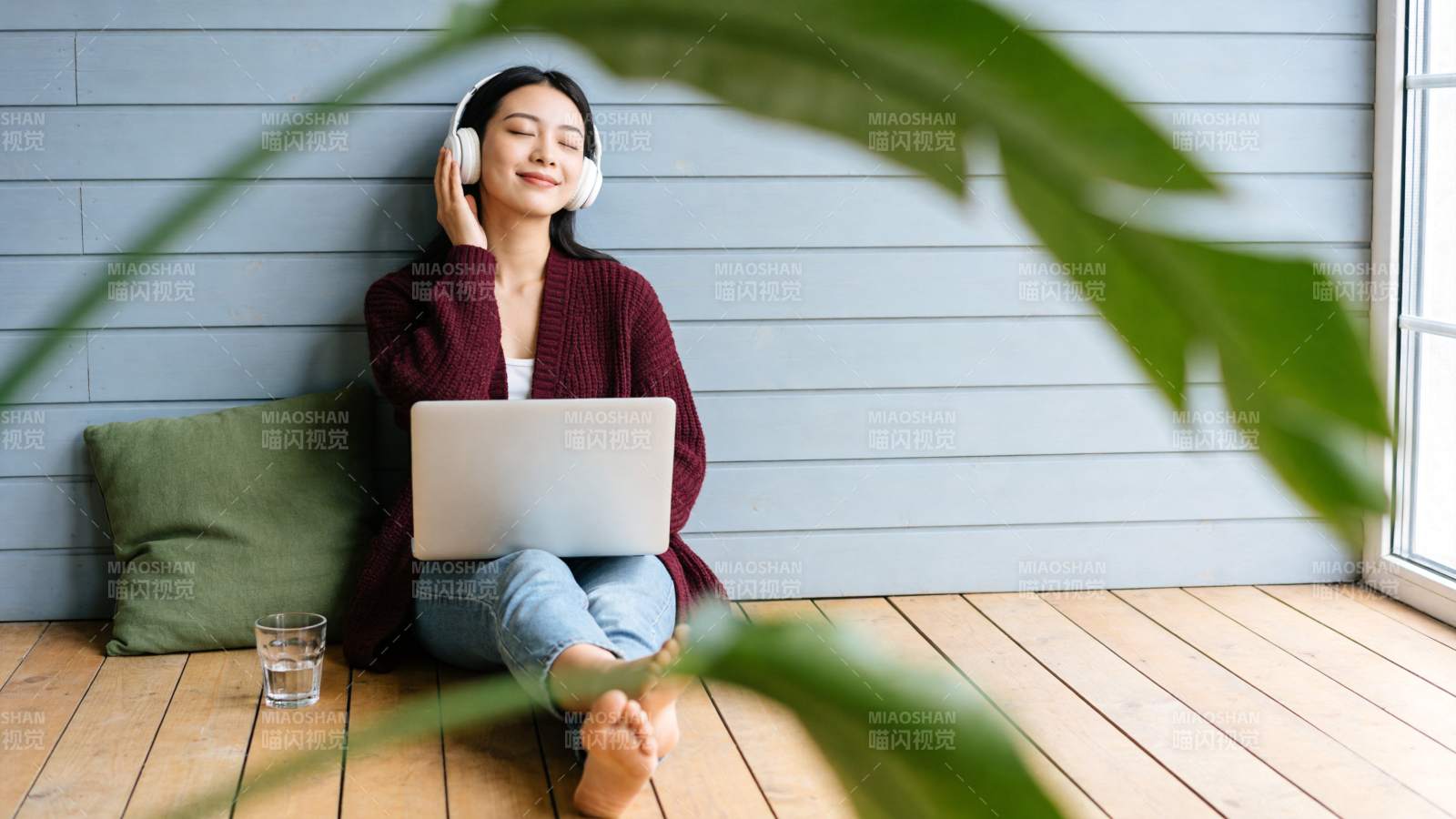 女子戴耳机坐地板用笔记本电脑听音乐图片
