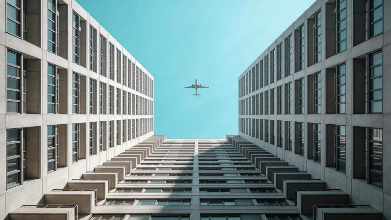 高楼夹缝中飞行的客机仰视视角图片