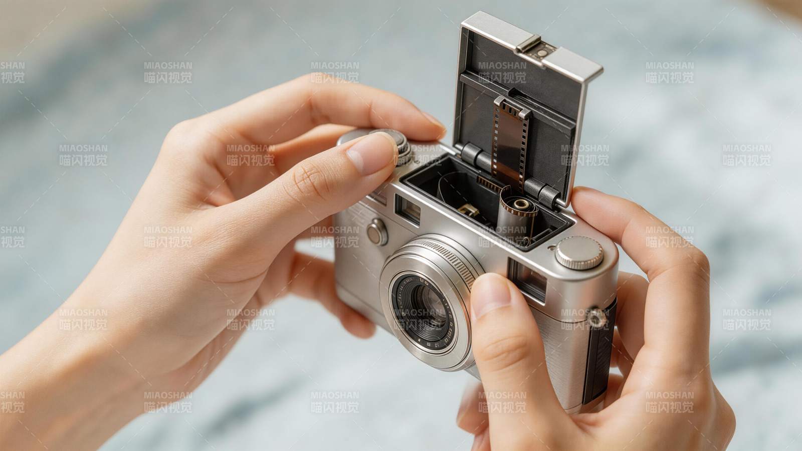 双手操作银色胶片相机装入胶卷图片