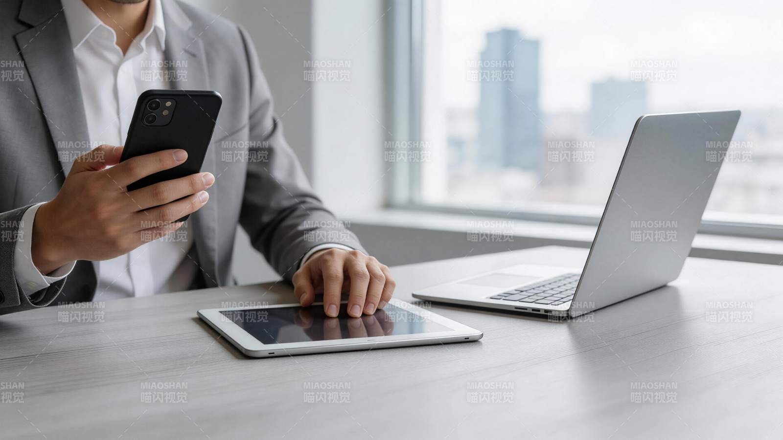 商务人士手持手机操作平板与笔记本电脑图片