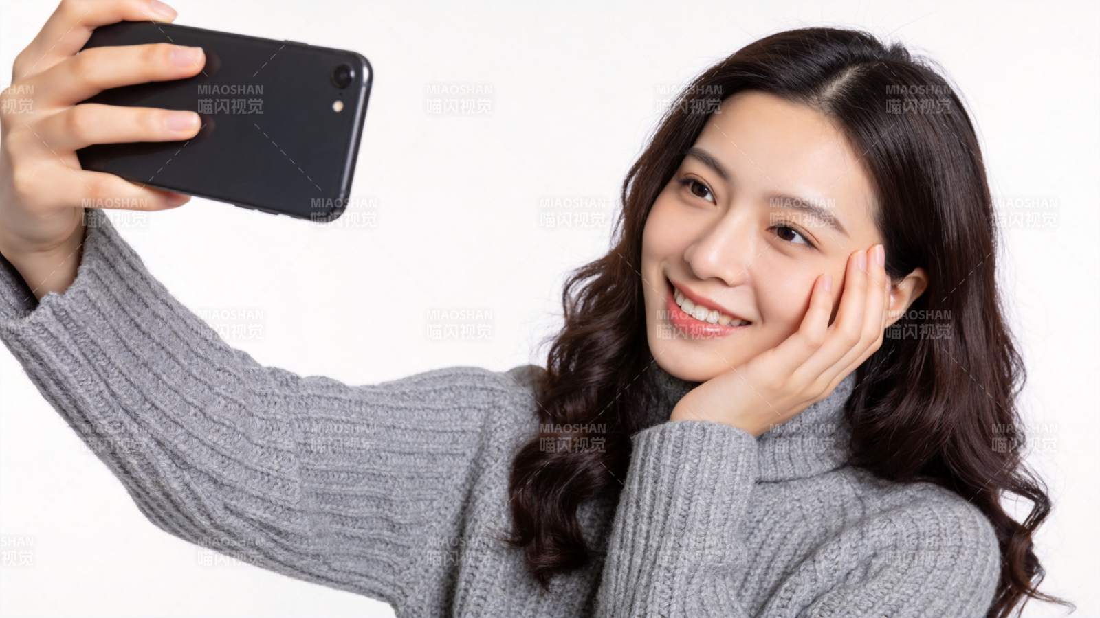 年轻女性手持黑色手机自拍微笑图片