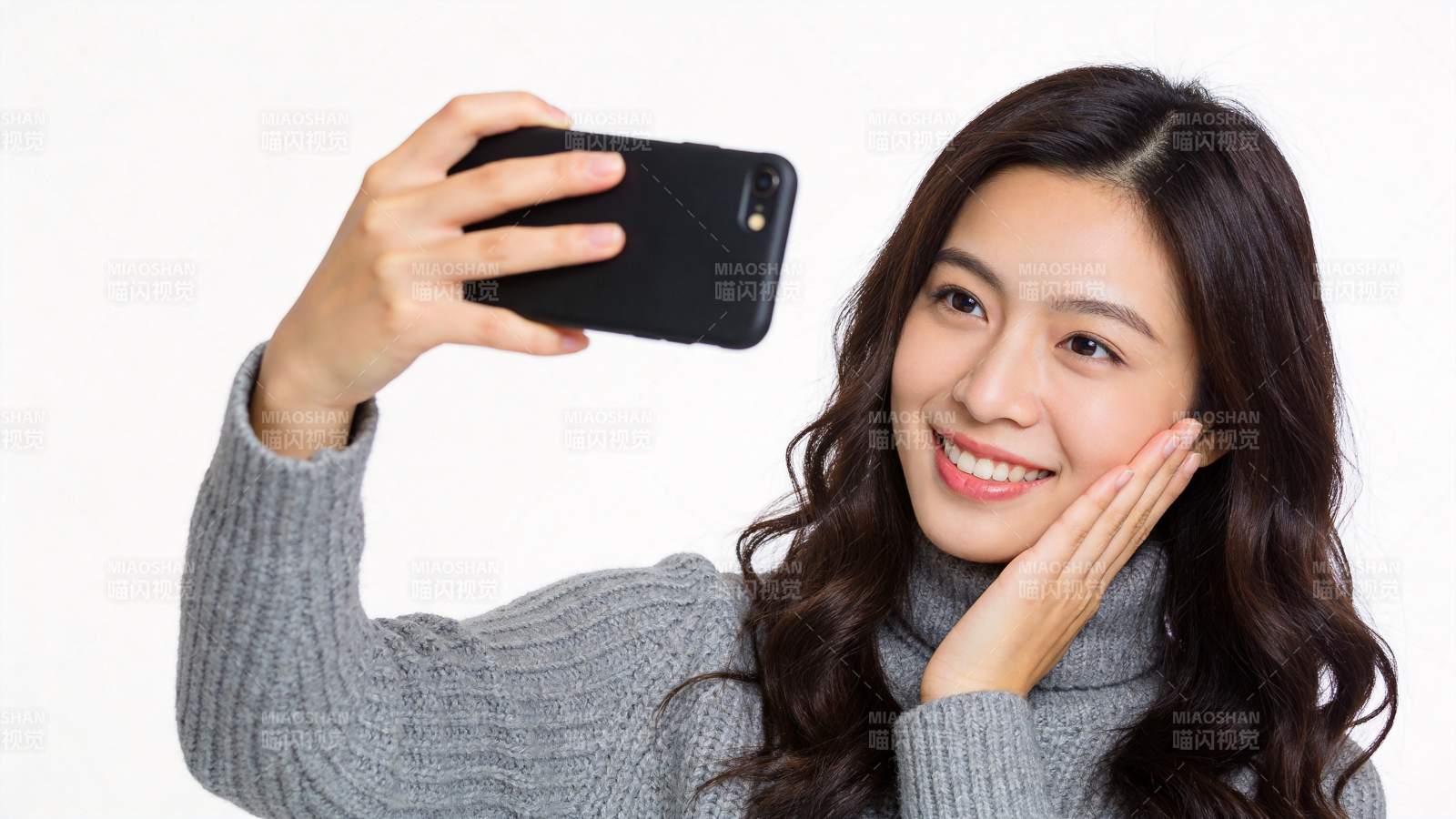 年轻女性手持黑色手机自拍微笑图片