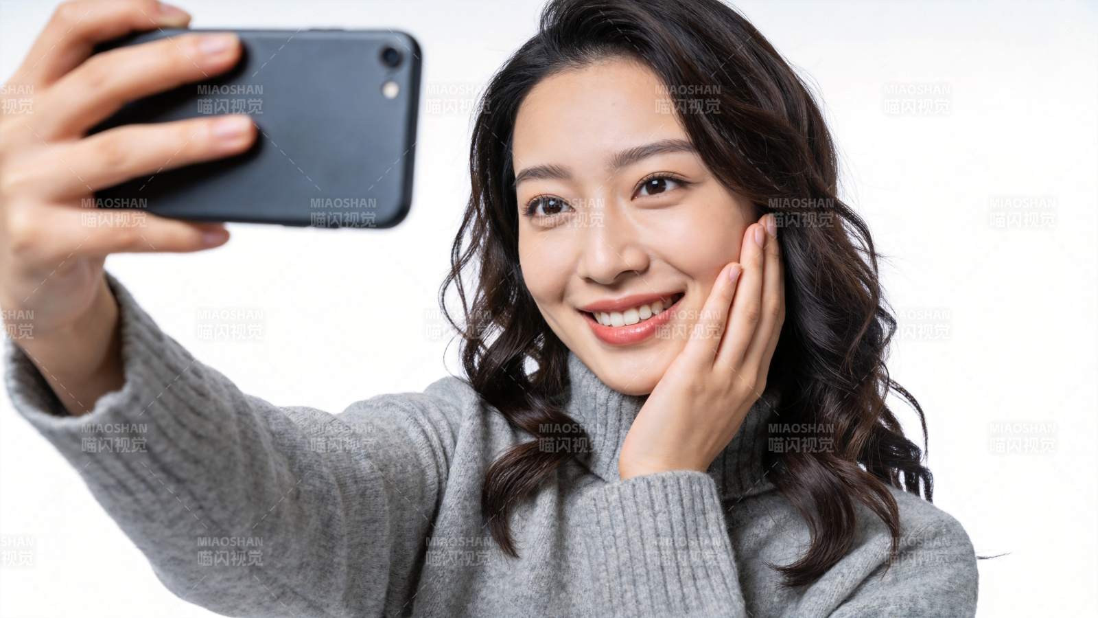 女性手持黑色手机自拍微笑特写图片