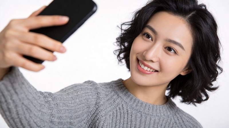 短发女性手持黑色手机自拍微笑图片