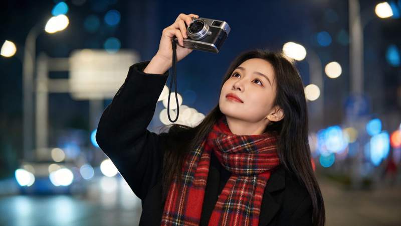 夜晚街头女子举相机仰拍城市灯光图片