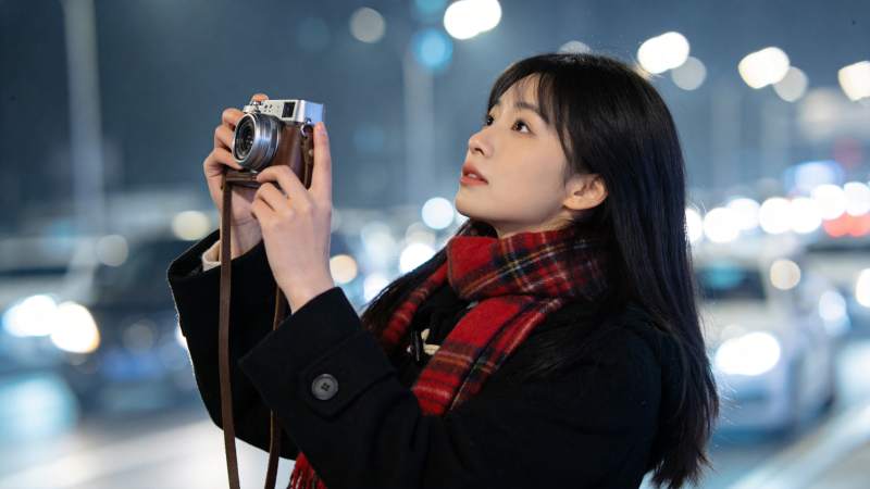 夜晚街头女子手持复古相机拍摄街景图片