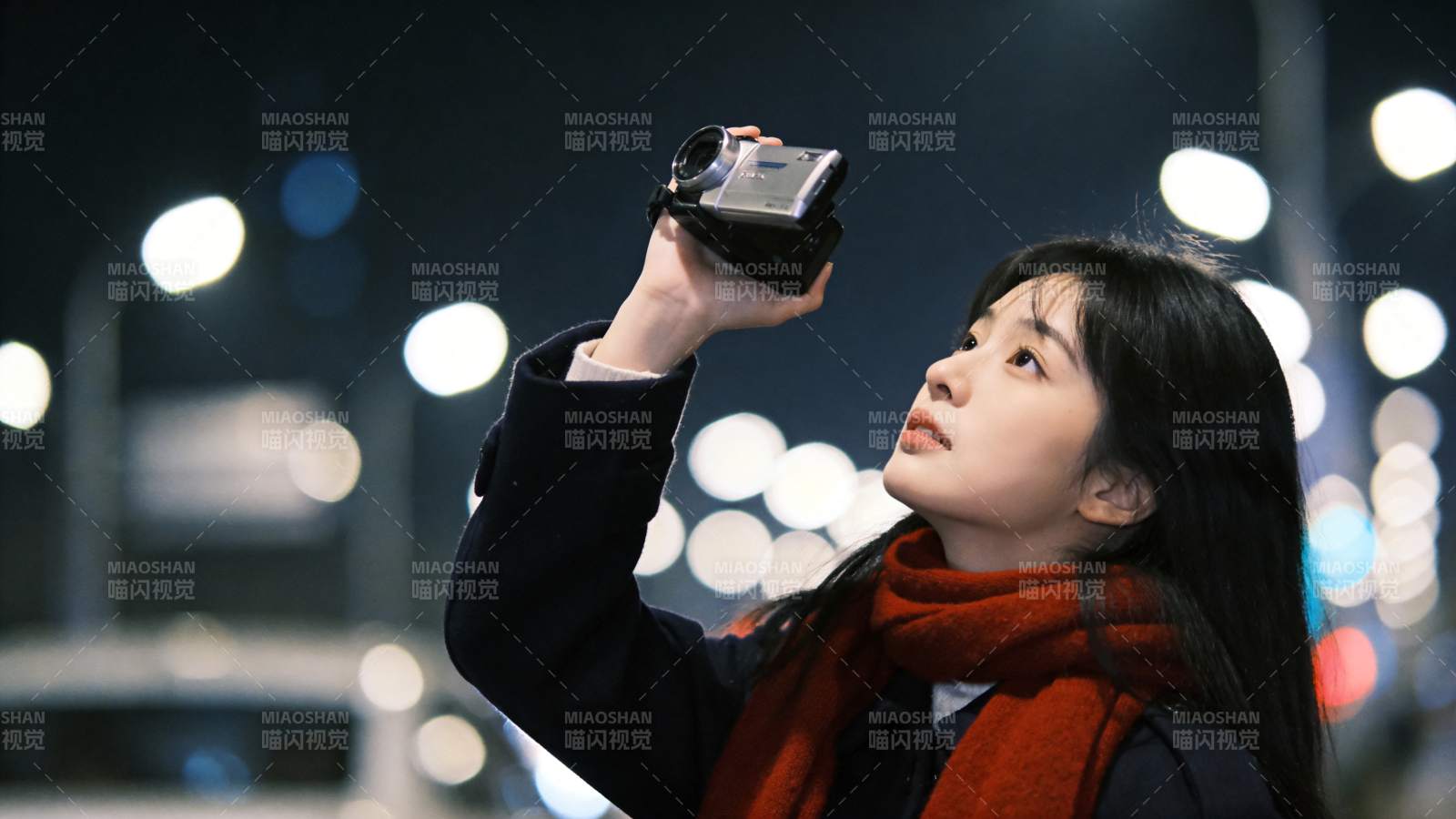 夜晚街头女子举摄像机仰拍夜景图片