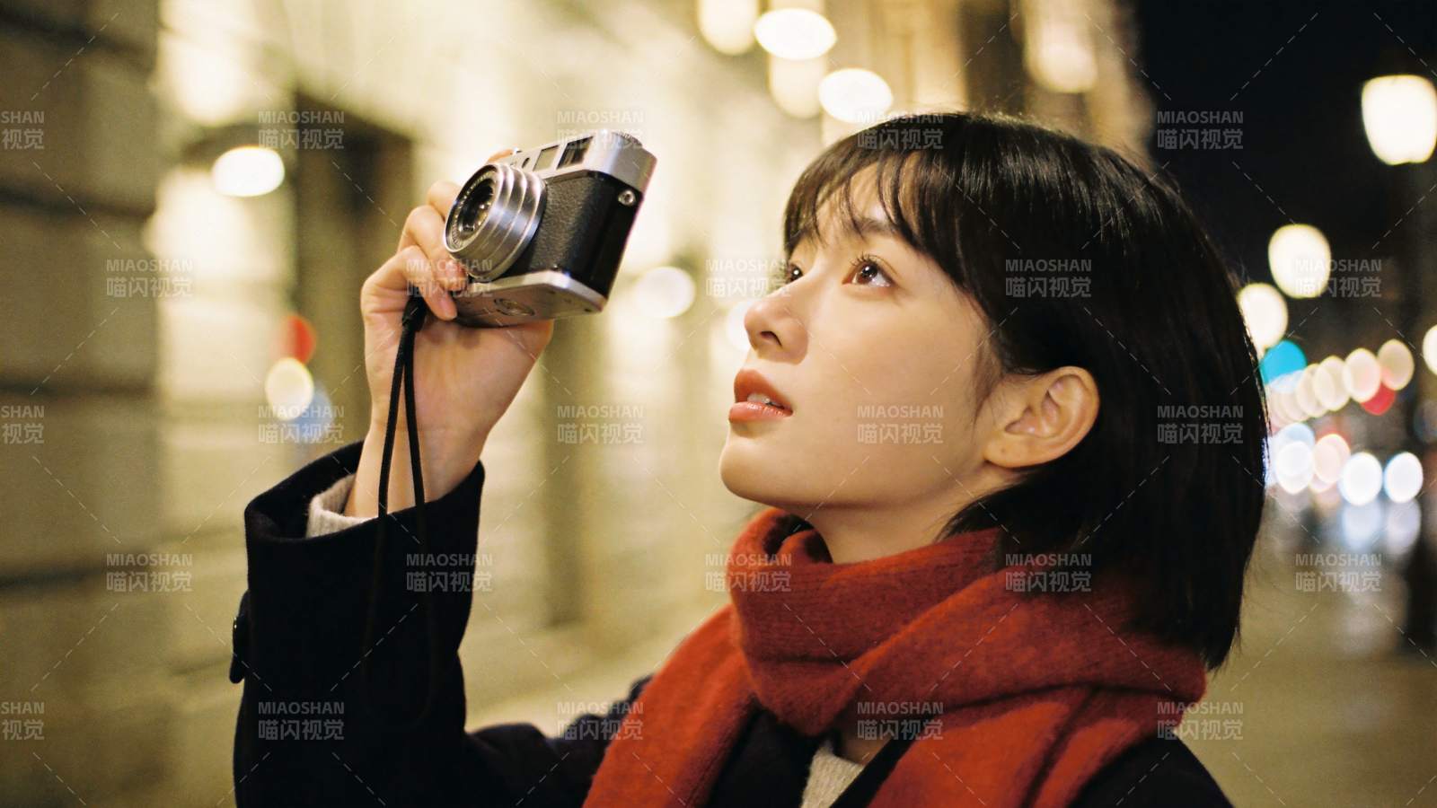 夜晚街头女子手持老式相机仰拍图片