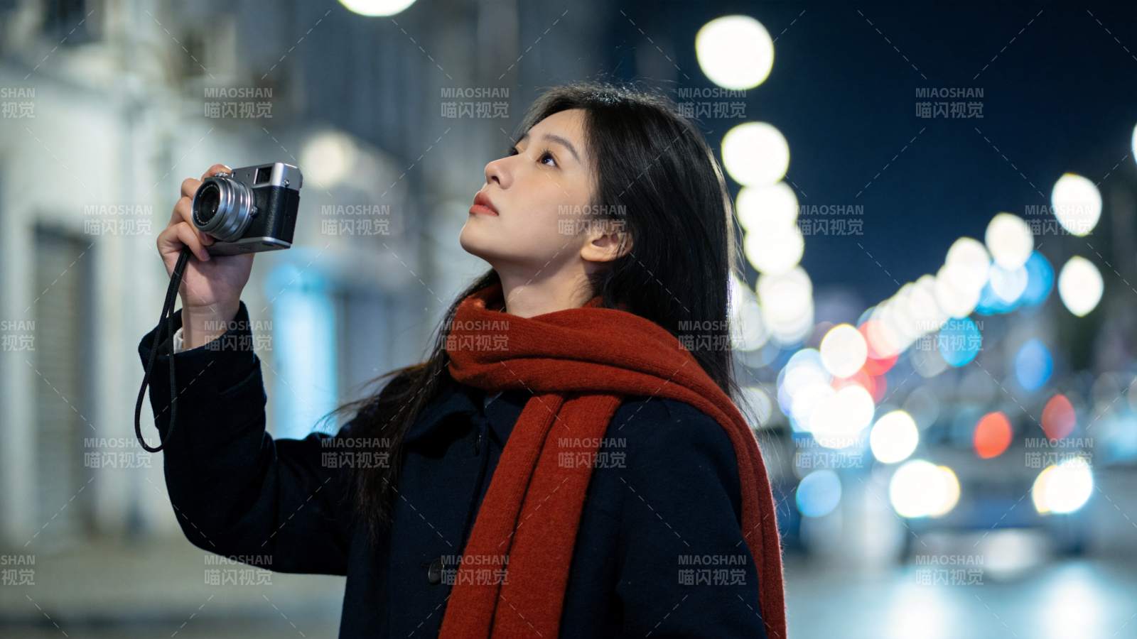 夜晚街头女子手持相机仰望拍摄图片