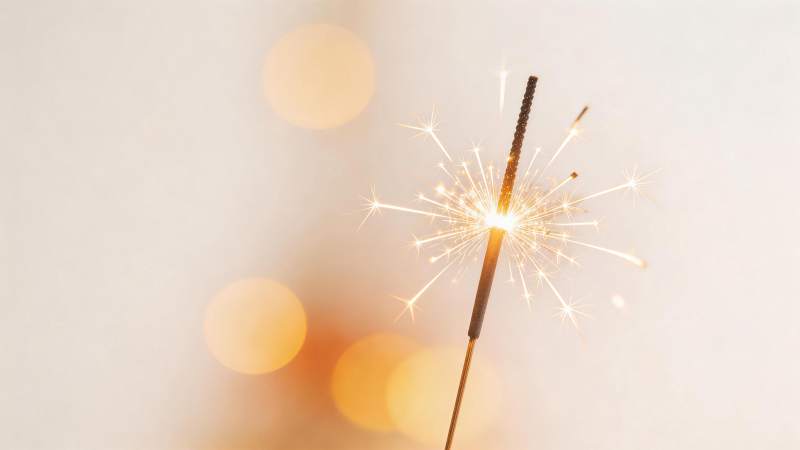 点燃的烟花棒在暖光背景中闪烁光芒图片