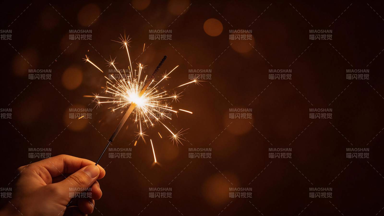 手持点燃的烟花棒发出明亮火花图片