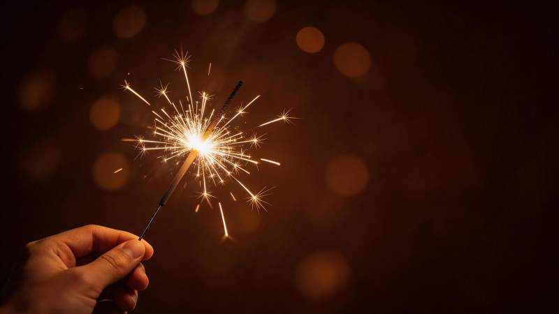 手持点燃的烟花棒发出明亮火花图片