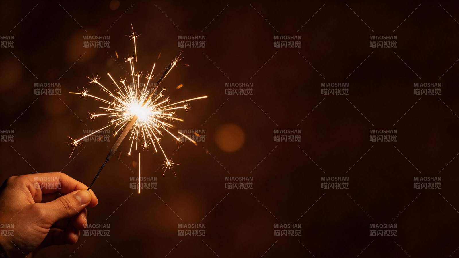 手持点燃的烟花棒发出明亮火花图片