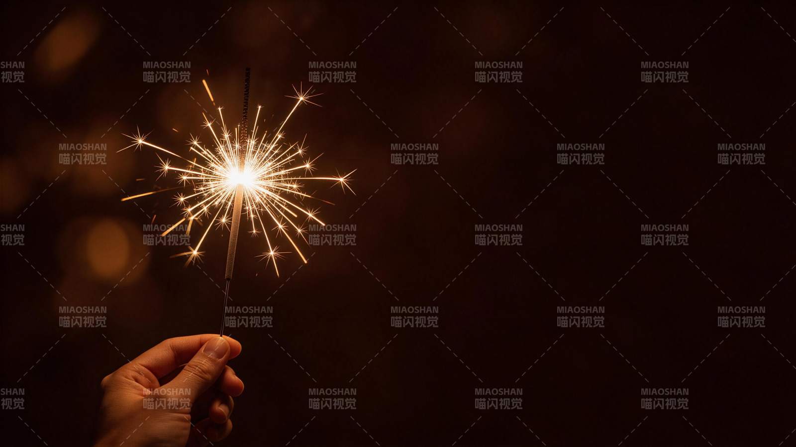 手持点燃的烟花棒在暗色背景中闪烁图片