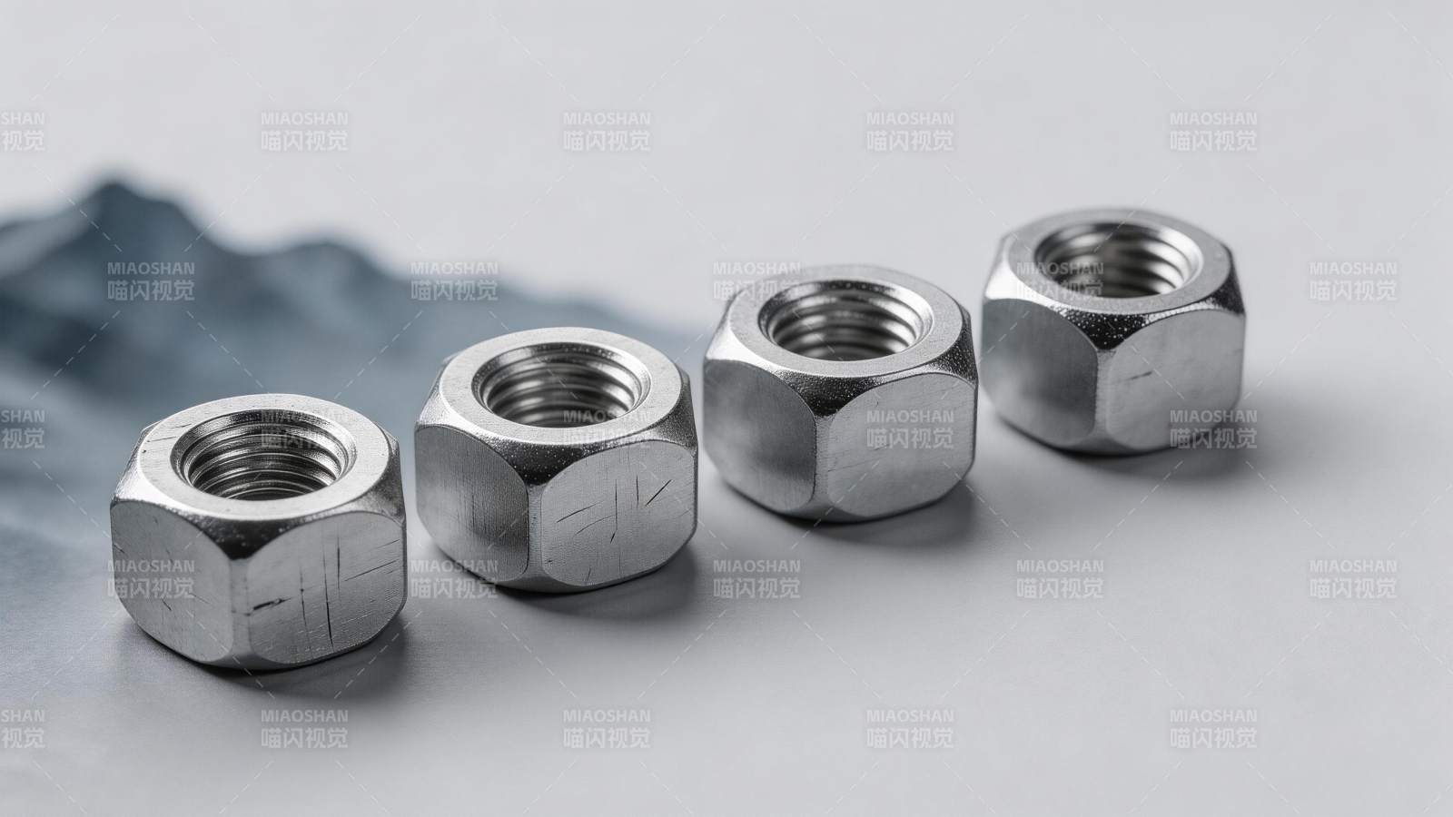 四个金属六角螺母排列在浅灰背景上图片