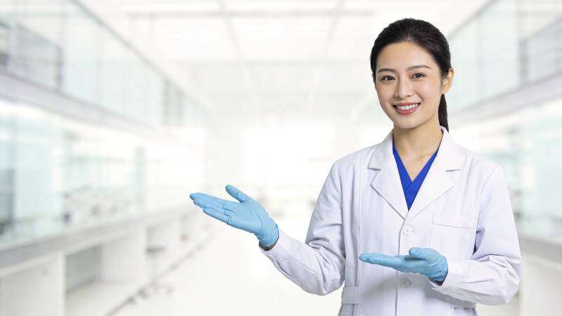 穿白大褂戴蓝手套的女性科研人员展示手势图片
