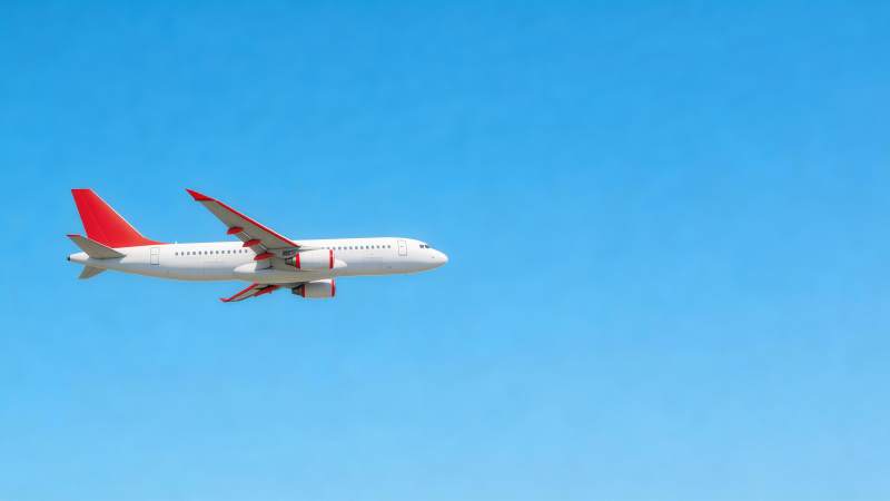 白色客机红尾翼蓝天飞行中图片