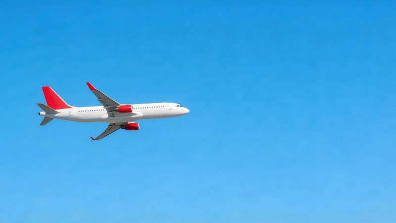 白色客机红尾翼蓝天飞行中图片