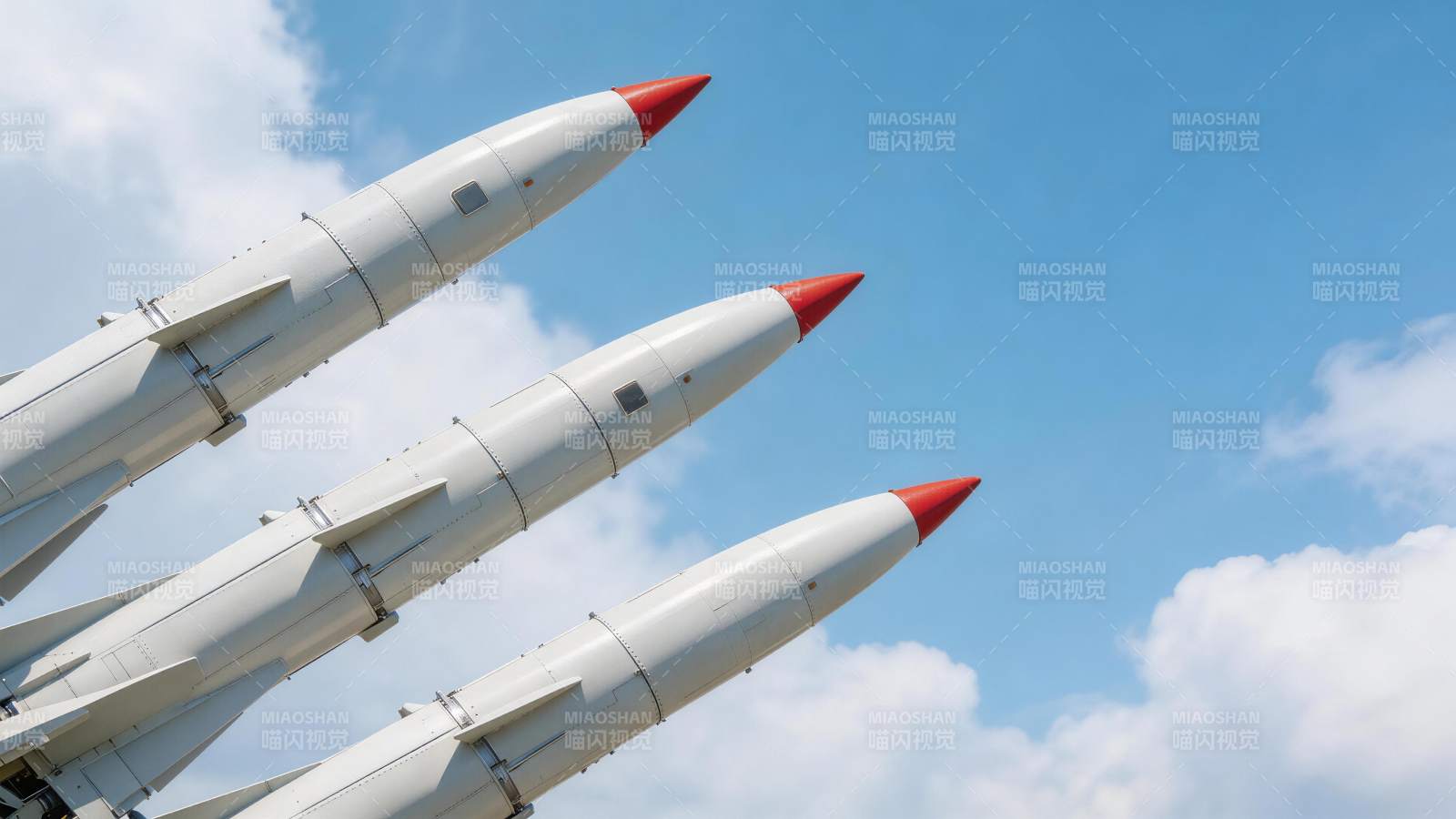 三枚白色导弹斜向排列指向蓝天背景图片