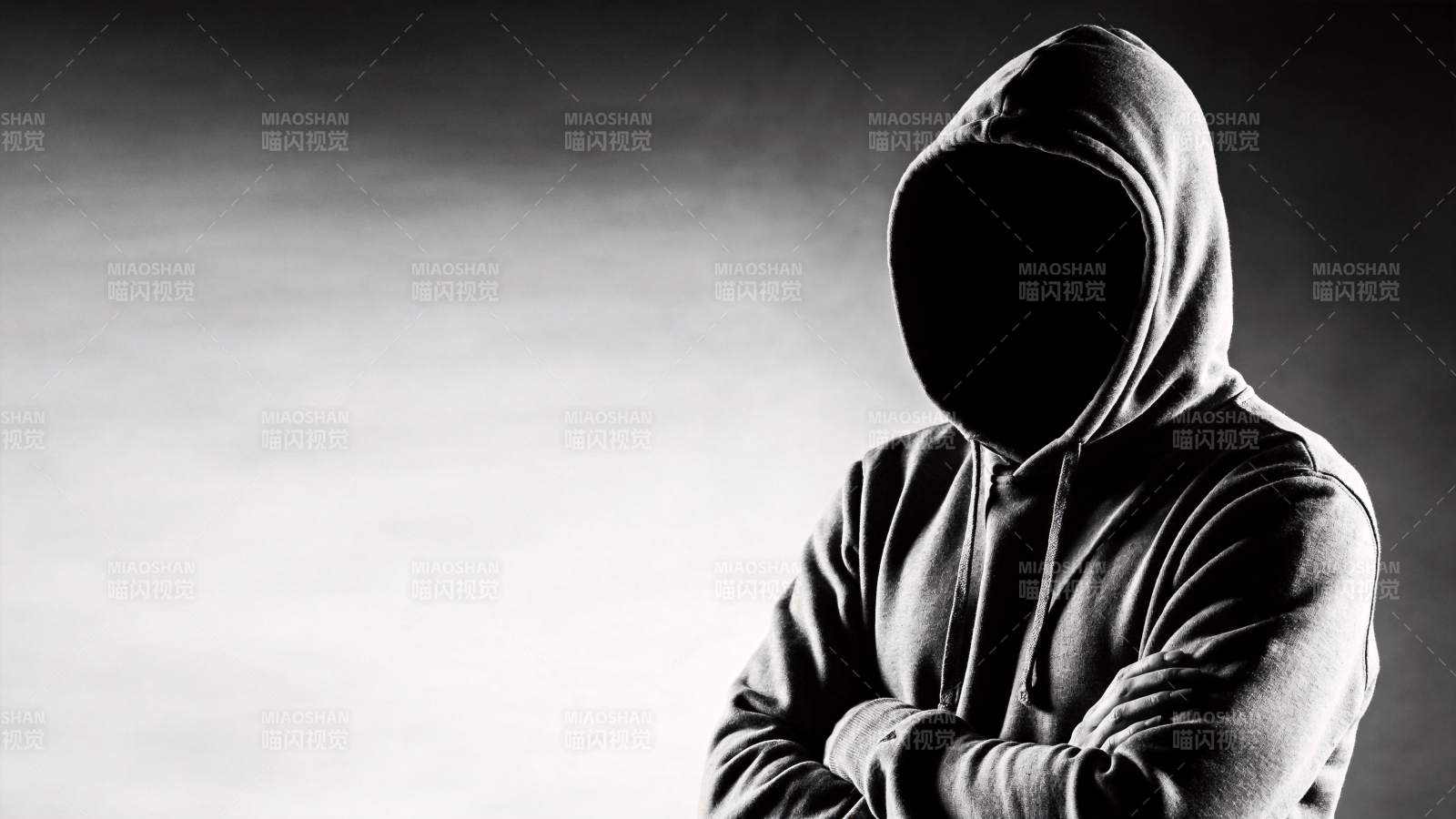 戴兜帽人物双臂交叉站立黑白影像图片