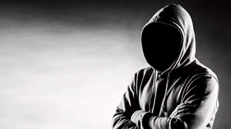 戴兜帽人物双臂交叉站立黑白影像图片