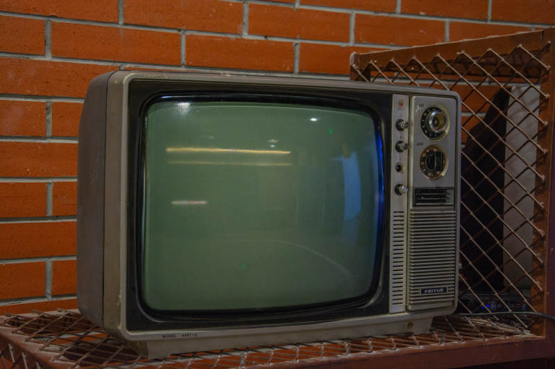 老式电视机静置砖墙前图片