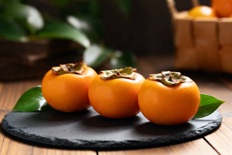 三颗柿子静置石盘图片