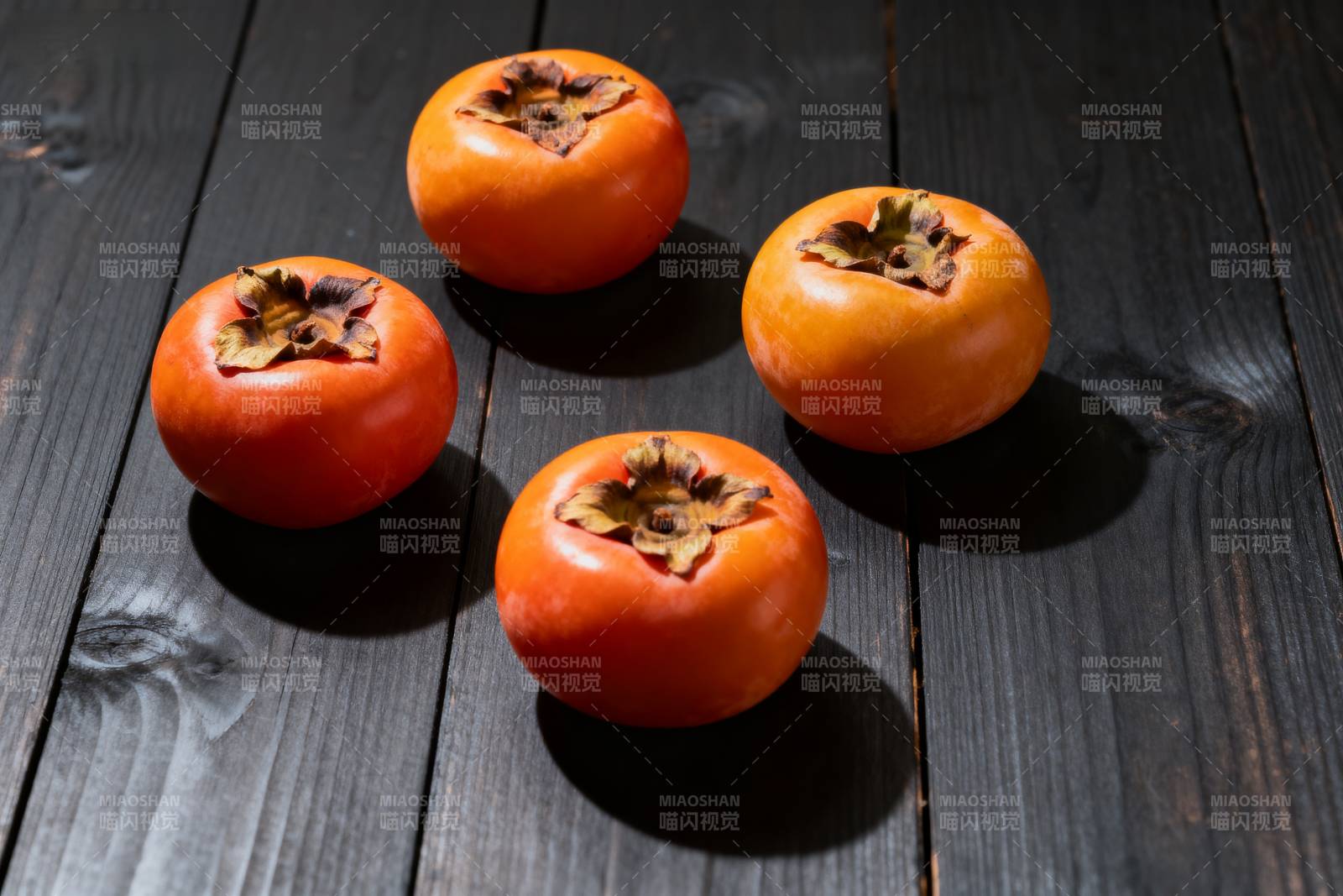 四颗柿子静置于木桌图片