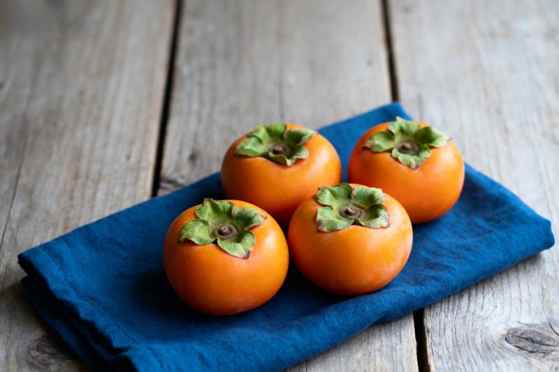 四颗柿子静置于蓝布图片