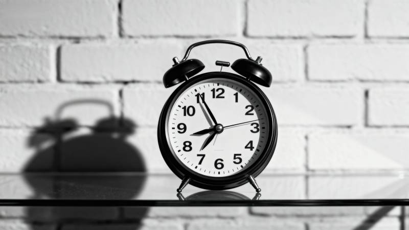 闹钟静置砖墙前图片