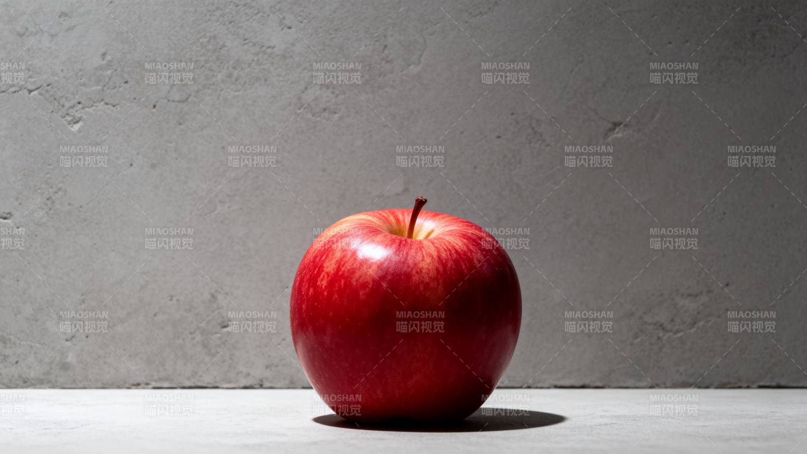 红苹果静置灰墙前图片