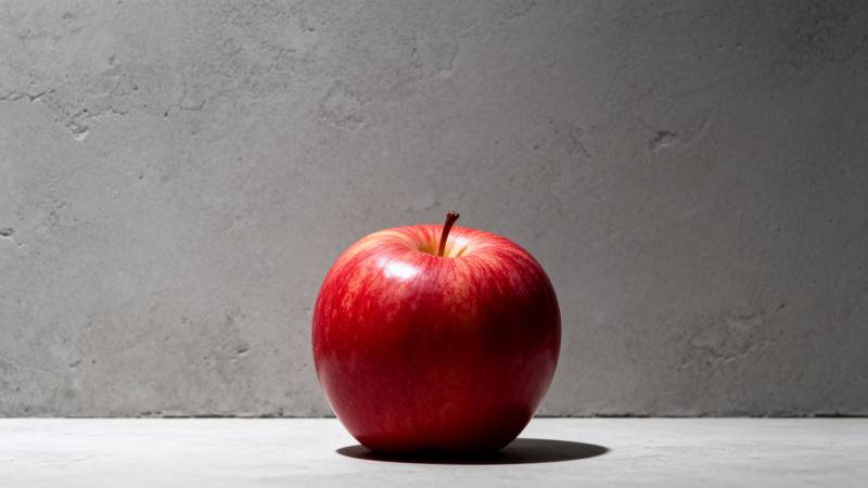 红苹果静置灰墙前图片
