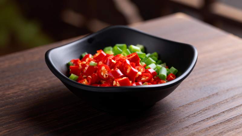 彩椒丁盛于黑碗中图片