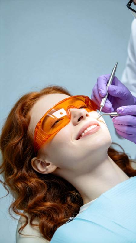 红发女子戴橙色护目镜接受牙科检查图片