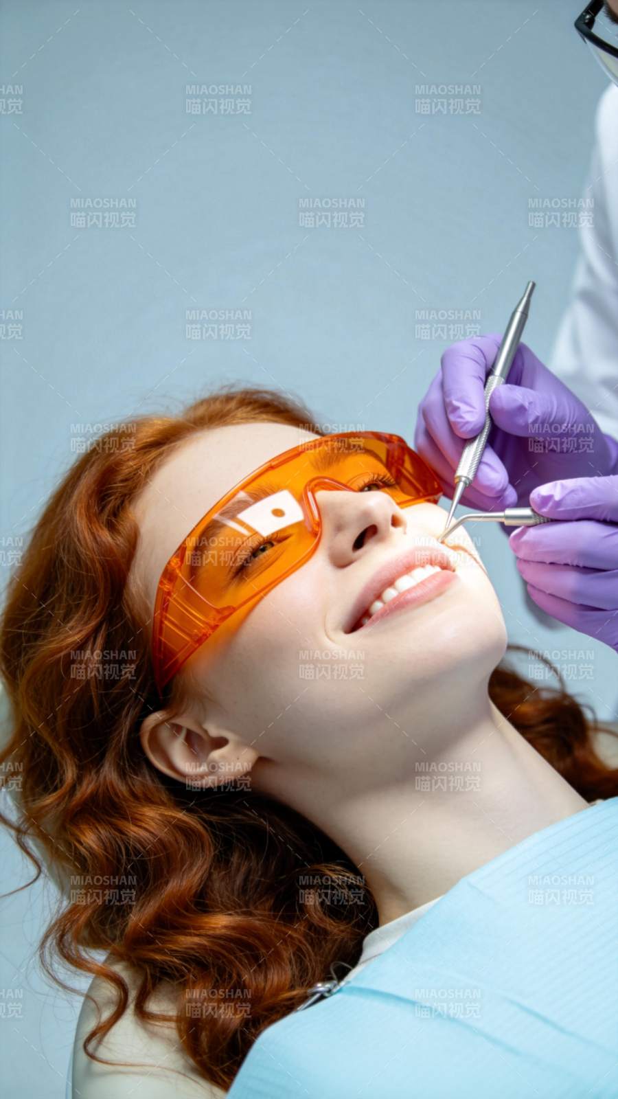 红发女子戴橙色护目镜接受牙科检查图片