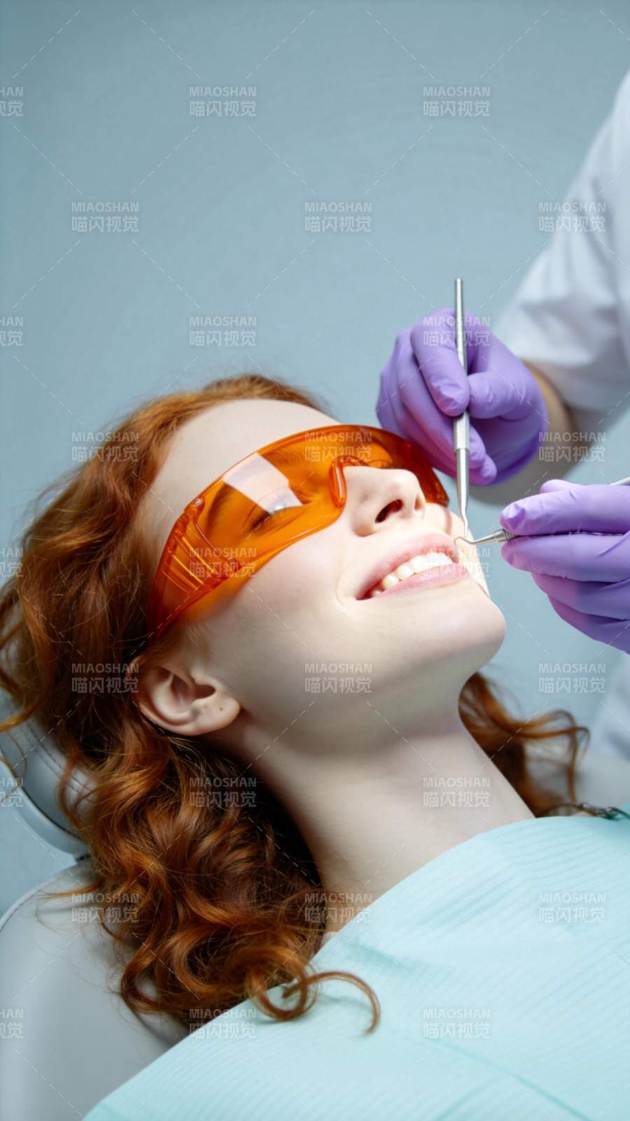 红发女子戴橙色护目镜接受牙科检查图片