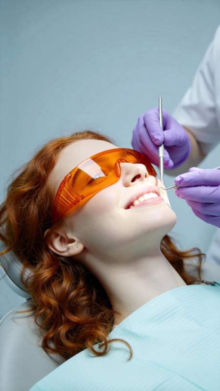 红发女子戴橙色护目镜接受牙科检查图片