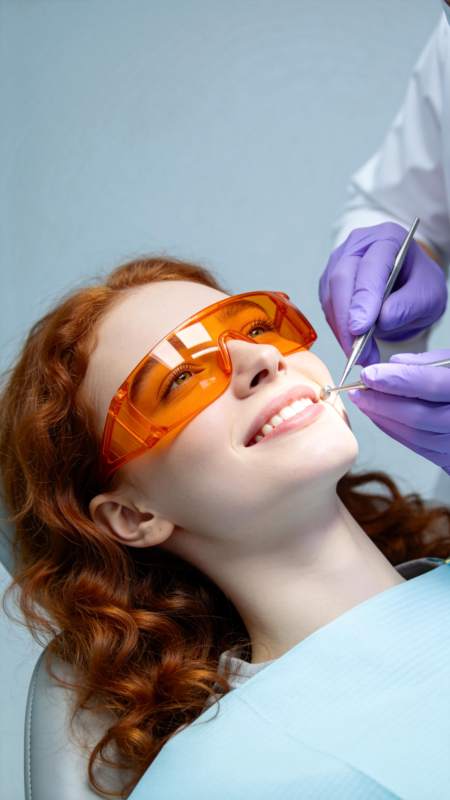 红发女子戴橙色护目镜接受牙科检查图片