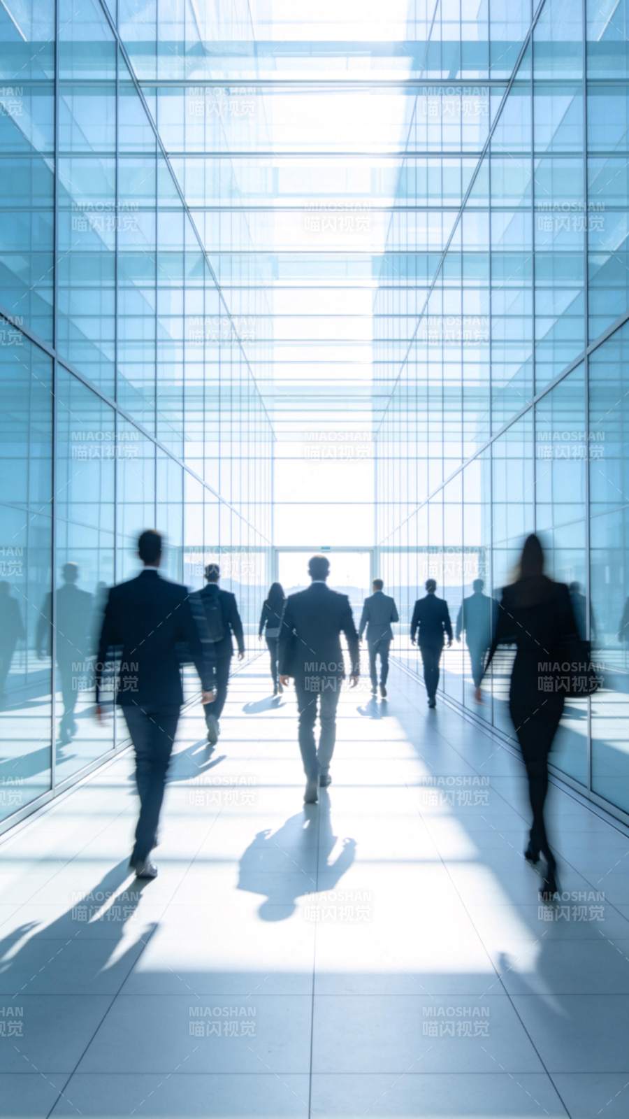 玻璃幕墙走廊中行走的商务人士剪影图片