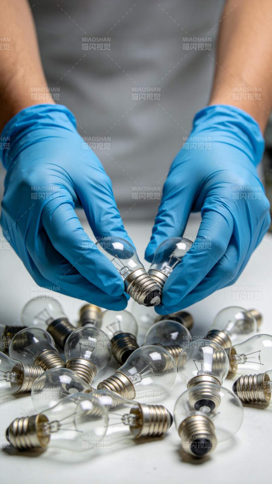 戴蓝色手套双手持白炽灯泡特写图片