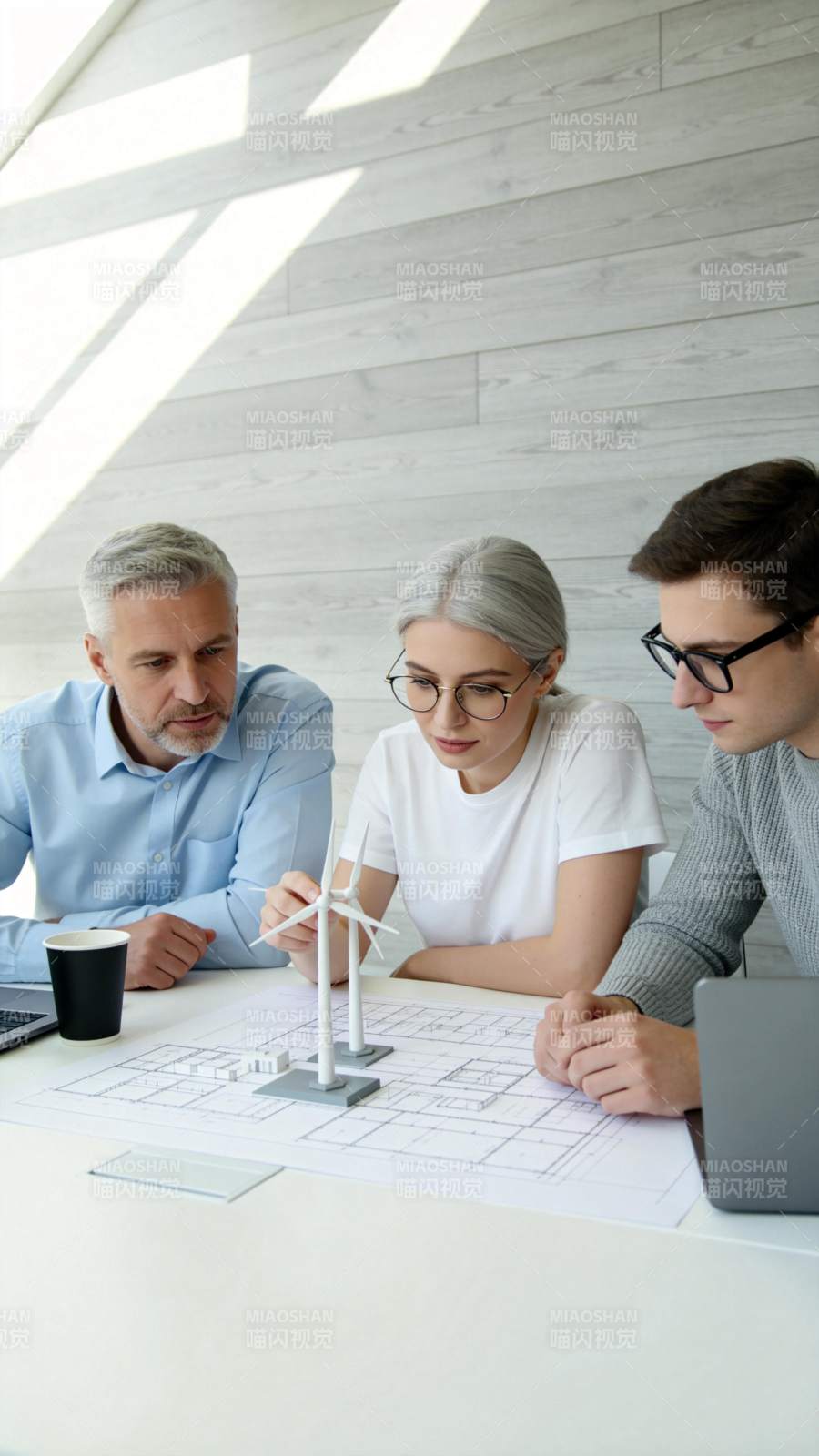 三人围桌研讨风力发电机模型与图纸图片