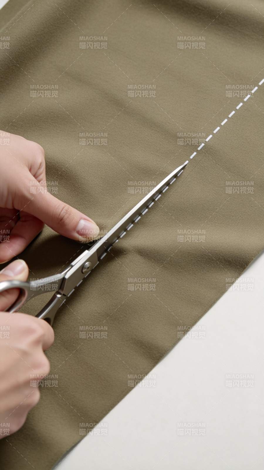 手持剪刀沿虚线裁剪卡其色布料图片