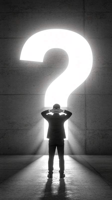 男子背对巨大发光问号站立沉思图片