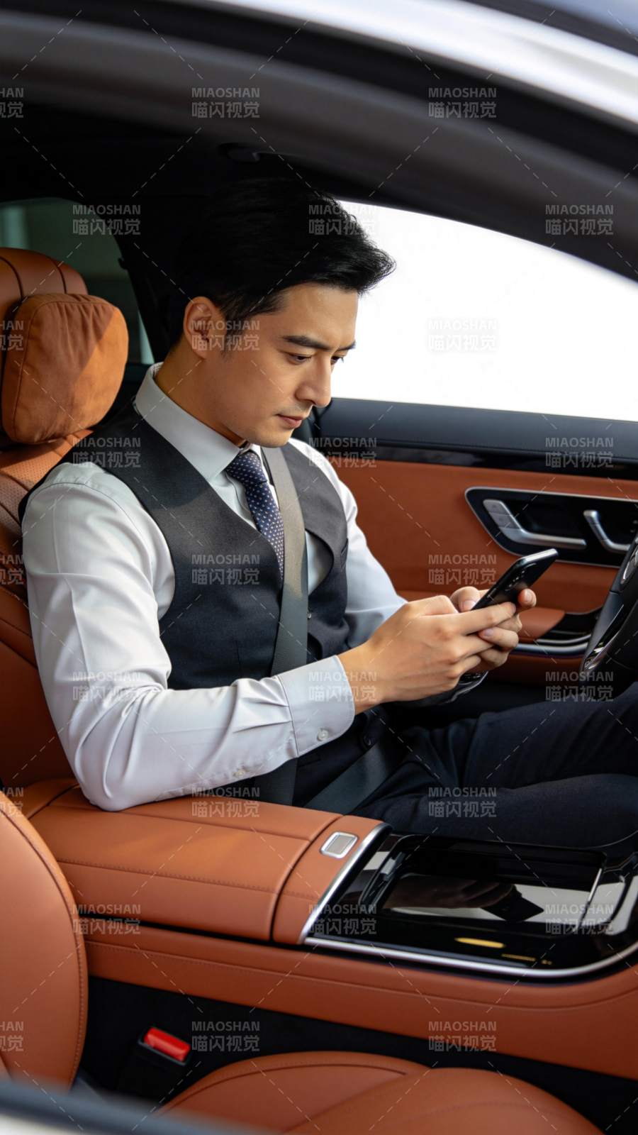 男士身着西装马甲坐在豪华车内使用手机图片