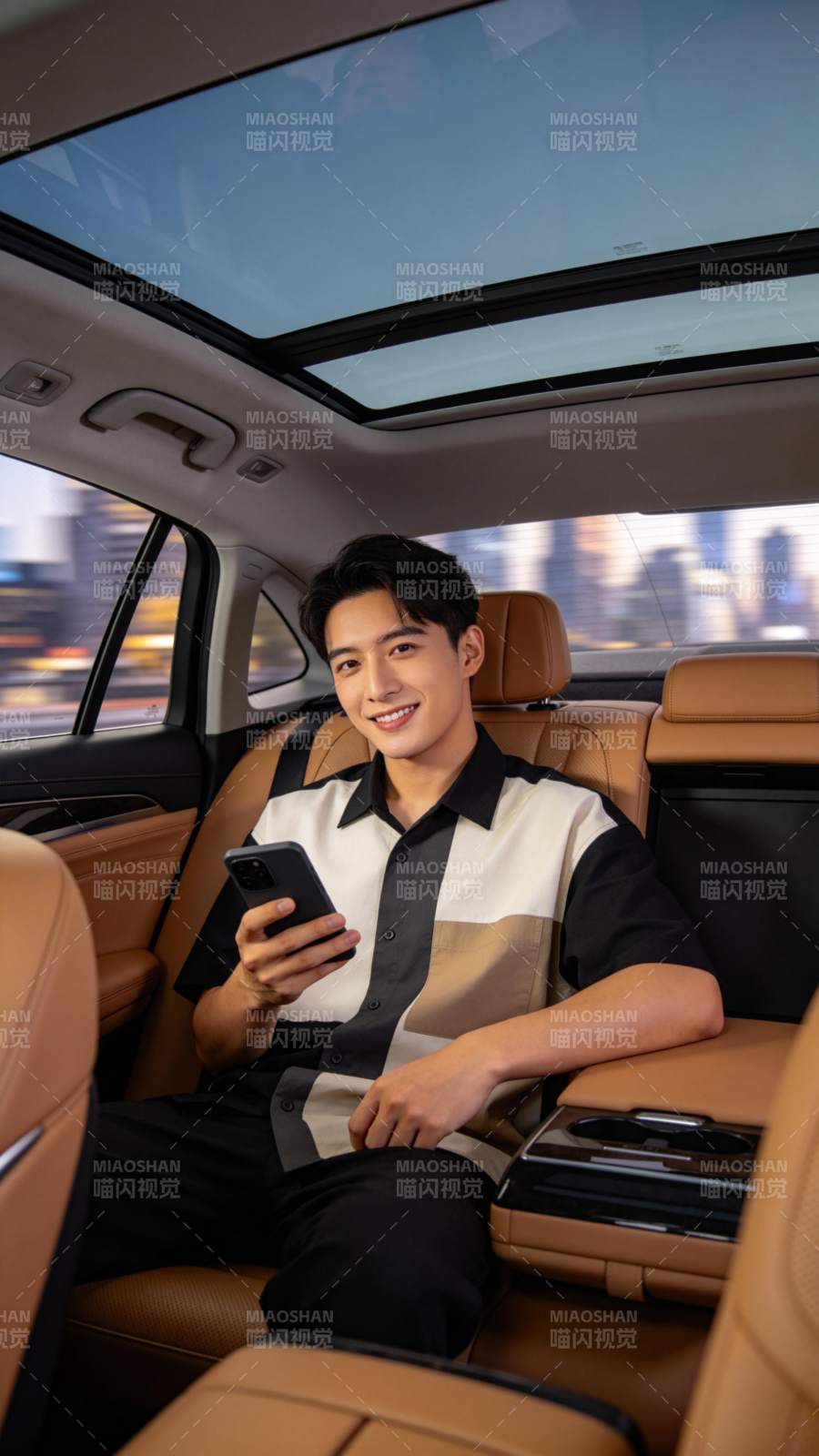 男子坐豪华车后排手持手机微笑图片