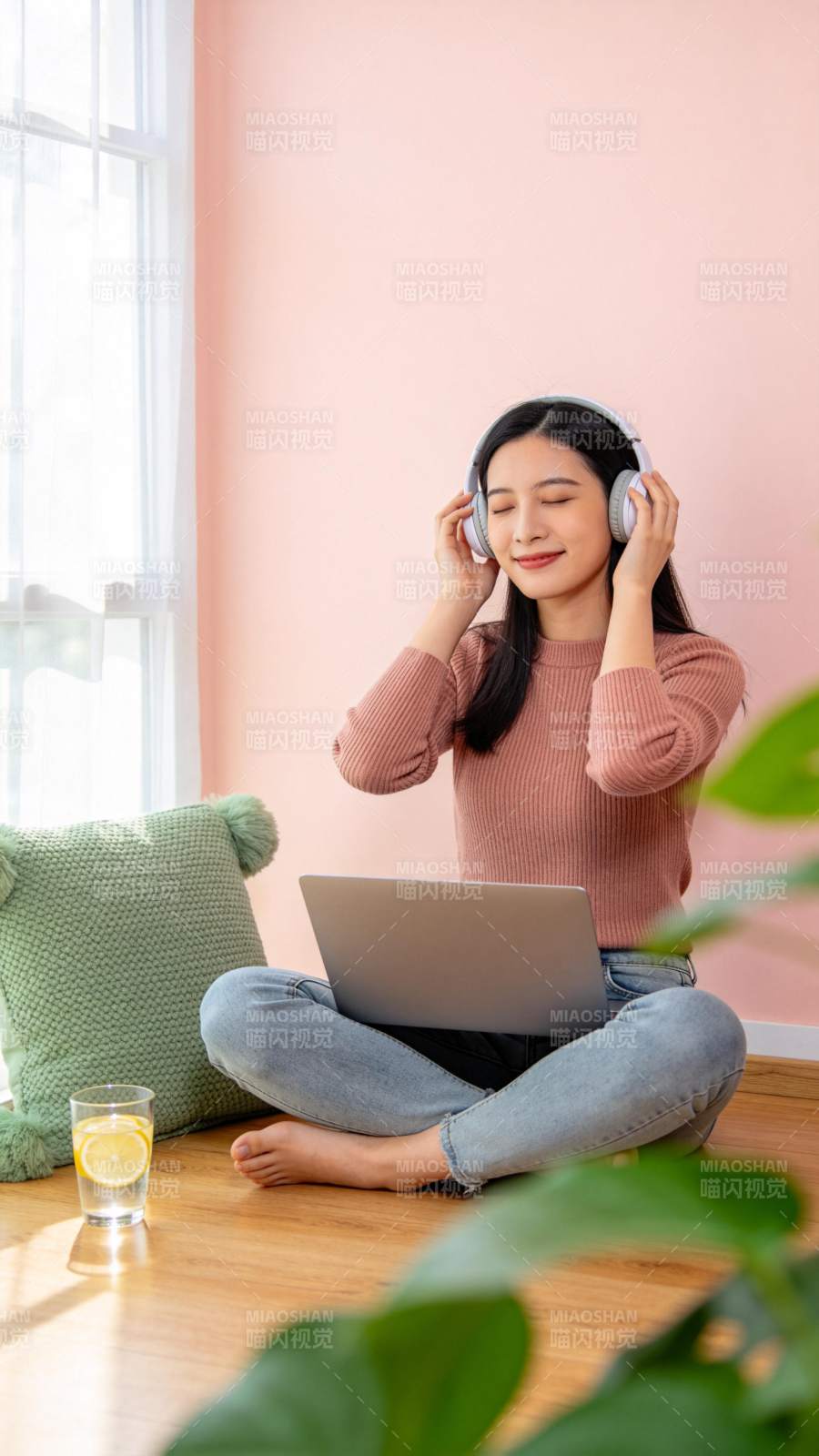 女子盘坐地板戴耳机使用笔记本电脑图片