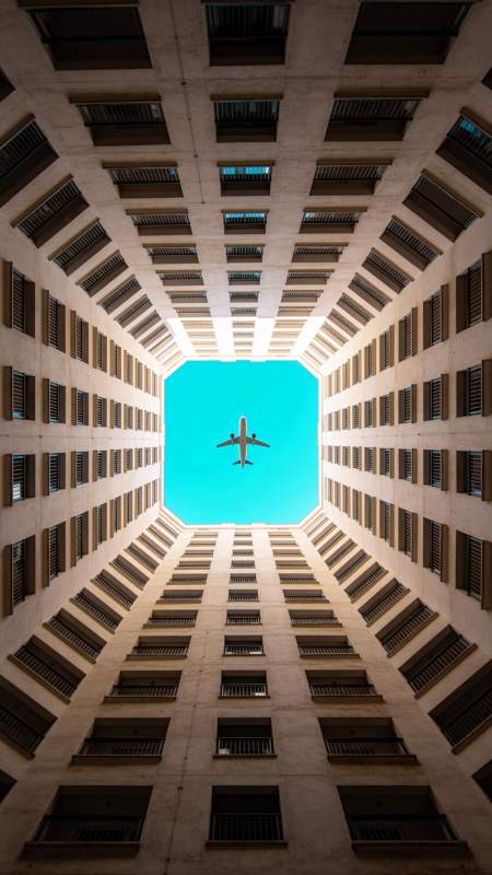 仰视高楼天井中飞过的客机图片