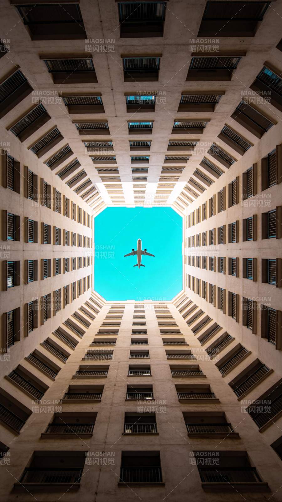 仰视高楼天井中飞过的客机图片